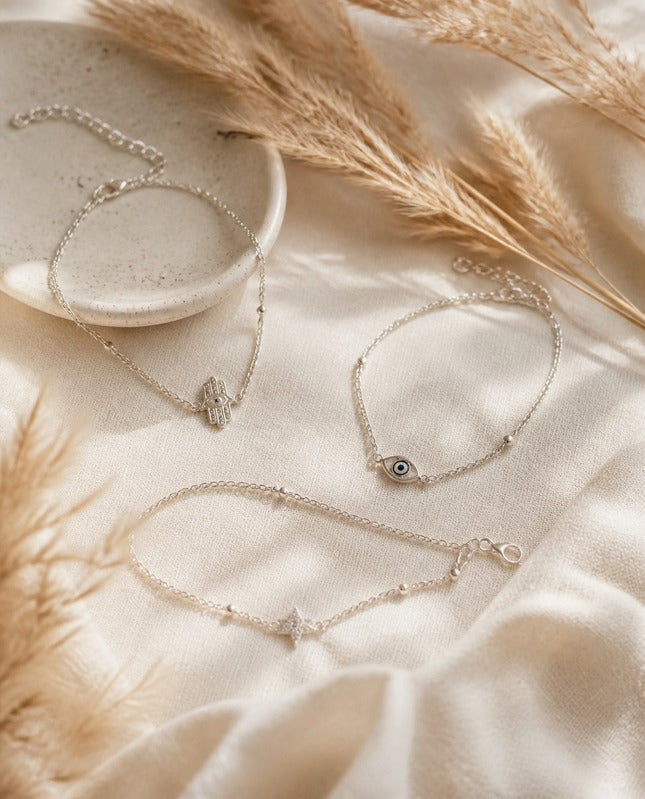 Pulseras de plata con dijes de protección sobre lino